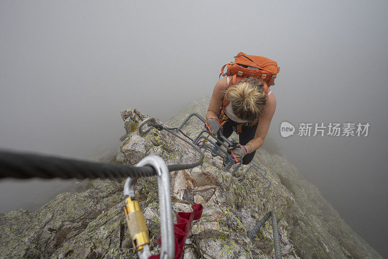 在雾中，一名女子爬上via ferrata
